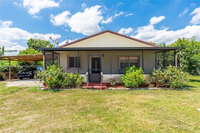 back of property with an attached carport, a lawn, and driveway