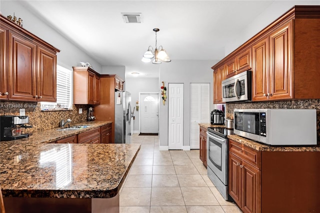 kitchen with brown cabinetry, visible vents, stainless steel appliances, and pendant lighting