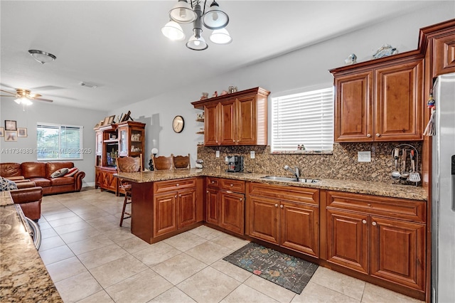 kitchen with stainless steel fridge, brown cabinetry, a breakfast bar, a peninsula, and a sink