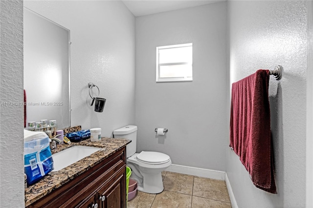 half bath featuring toilet, vanity, baseboards, and tile patterned floors