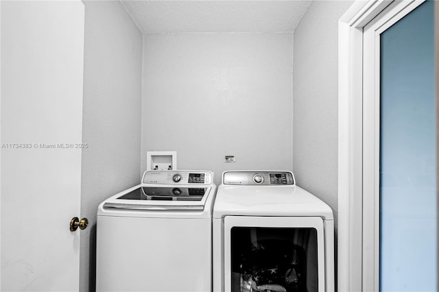 washroom with laundry area, washing machine and dryer, and a textured ceiling