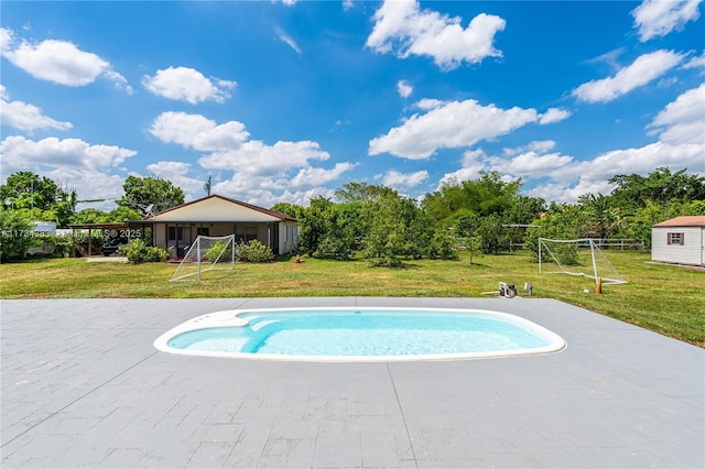 view of swimming pool with an outbuilding, a yard, and a shed