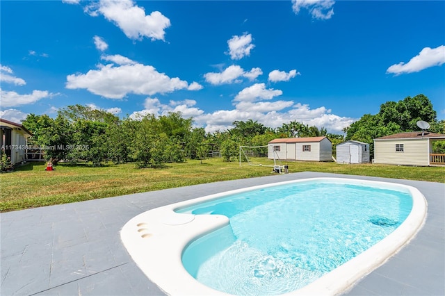 view of pool with a patio area, a yard, a storage unit, and an outdoor structure