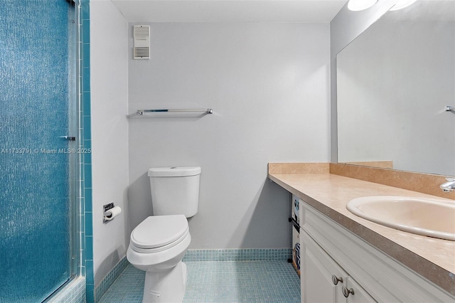 bathroom with tile patterned floors, toilet, an enclosed shower, and vanity