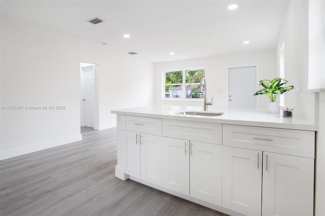 kitchen with white cabinetry, sink, and light hardwood / wood-style flooring