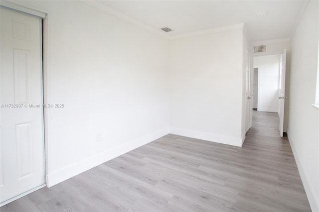 empty room with crown molding and light wood-type flooring