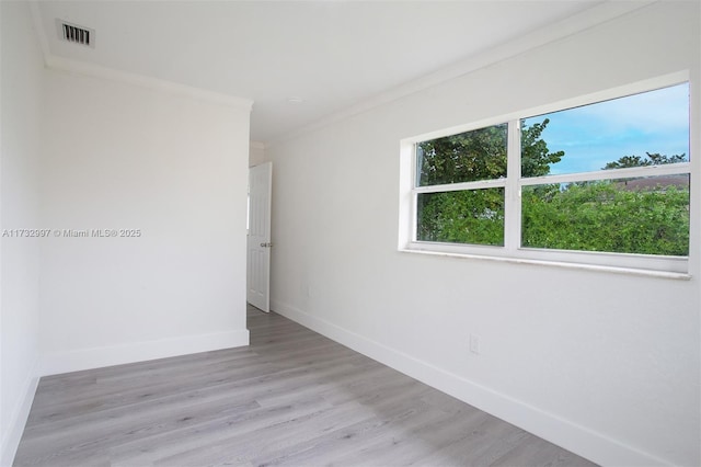 spare room with ornamental molding and light wood-type flooring