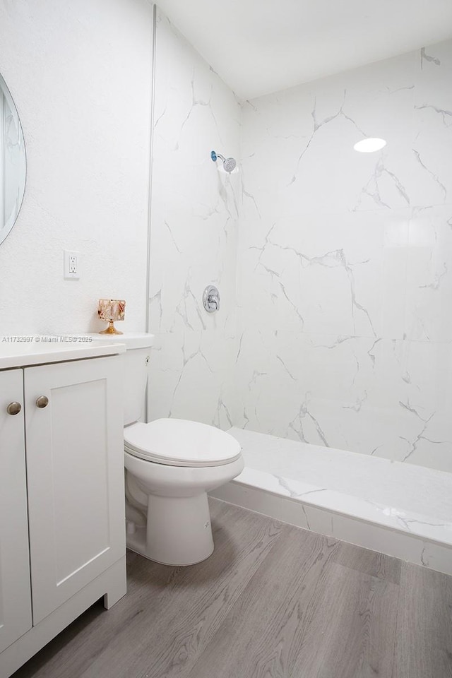 bathroom with vanity, a shower, hardwood / wood-style floors, and toilet