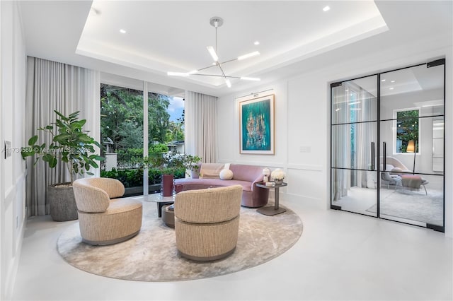 living area featuring recessed lighting, a raised ceiling, a chandelier, and finished concrete flooring