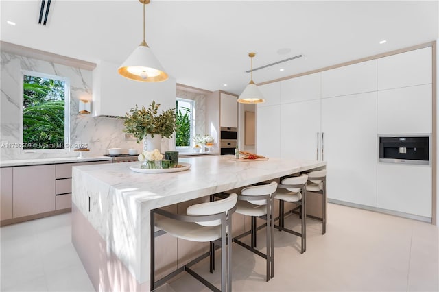 kitchen with decorative backsplash, light stone counters, modern cabinets, and a kitchen island