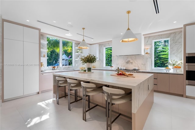 kitchen with tasteful backsplash, a center island, pendant lighting, a kitchen bar, and modern cabinets