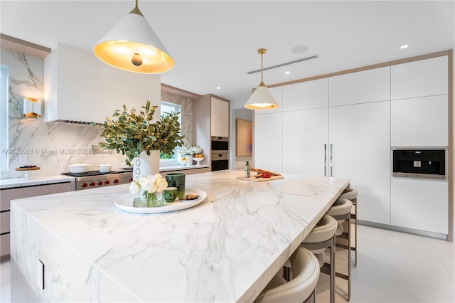 kitchen featuring pendant lighting, a breakfast bar, light stone counters, tasteful backsplash, and stainless steel gas cooktop