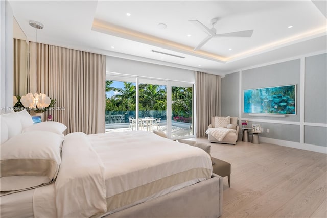 bedroom with visible vents, wood finished floors, a raised ceiling, and access to outside