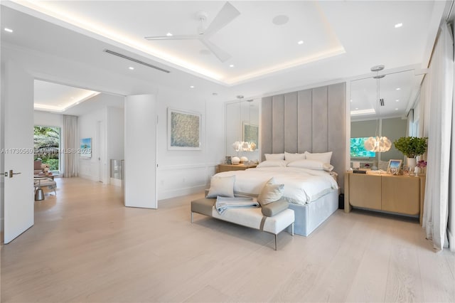 bedroom with visible vents, light wood-type flooring, and a raised ceiling