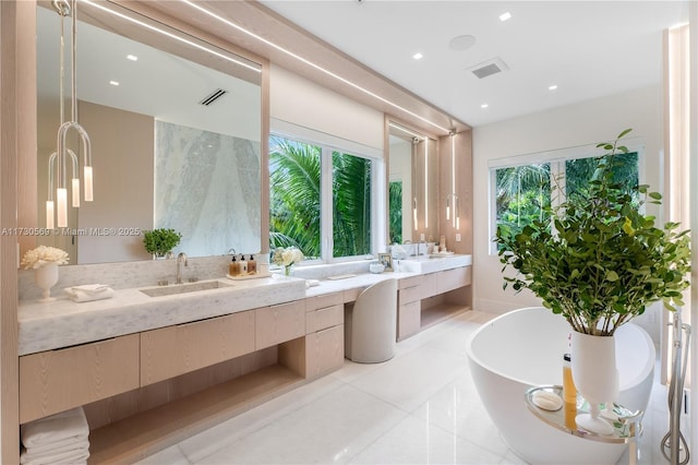 bathroom with visible vents, double vanity, a freestanding tub, tile patterned floors, and a sink