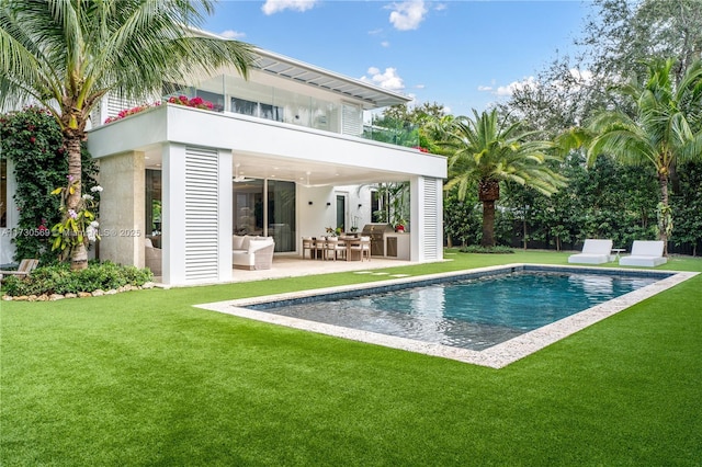 back of house with an outdoor pool, a yard, a patio, and a balcony