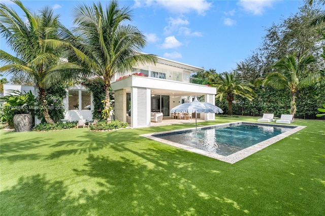 rear view of property with a patio area, a lawn, and an outdoor pool