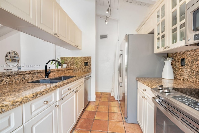 kitchen with tasteful backsplash, appliances with stainless steel finishes, sink, and white cabinets