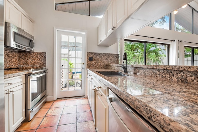 kitchen featuring white cabinetry, lofted ceiling, stainless steel appliances, and sink