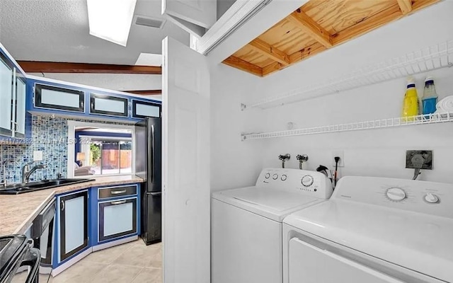 washroom featuring a textured ceiling, washer and dryer, indoor wet bar, and light tile patterned flooring