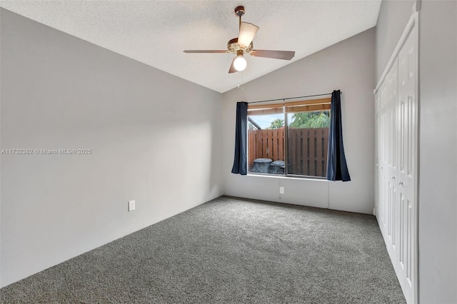 carpeted spare room featuring lofted ceiling, ceiling fan, and a textured ceiling