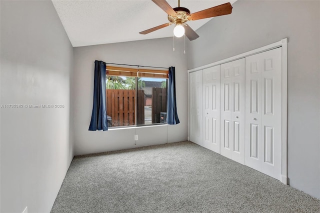 unfurnished bedroom with vaulted ceiling, carpet floors, ceiling fan, and a closet