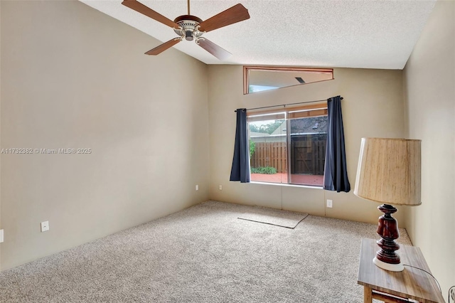 spare room featuring ceiling fan, lofted ceiling, carpet flooring, and a textured ceiling