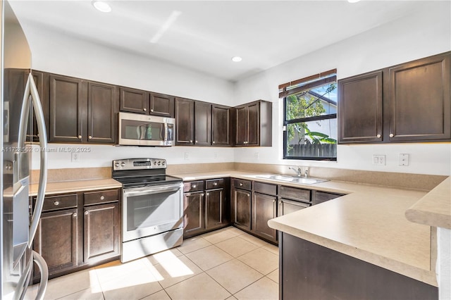 kitchen featuring light tile patterned floors, sink, appliances with stainless steel finishes, dark brown cabinets, and kitchen peninsula