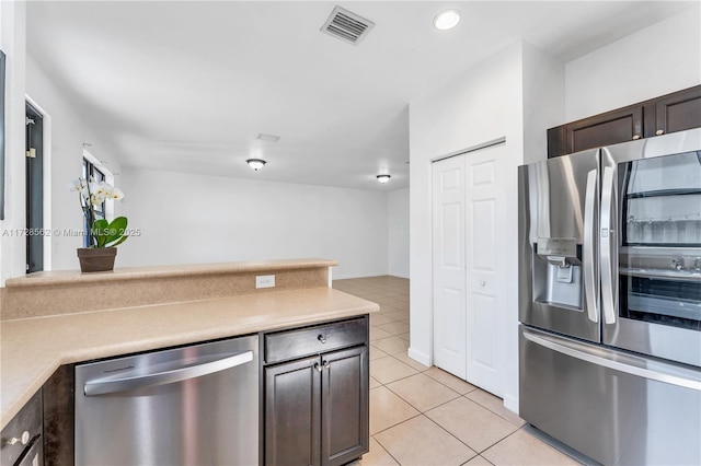 kitchen with light tile patterned floors, dark brown cabinets, and appliances with stainless steel finishes