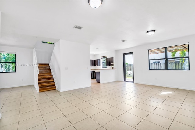 unfurnished living room featuring a healthy amount of sunlight and light tile patterned floors