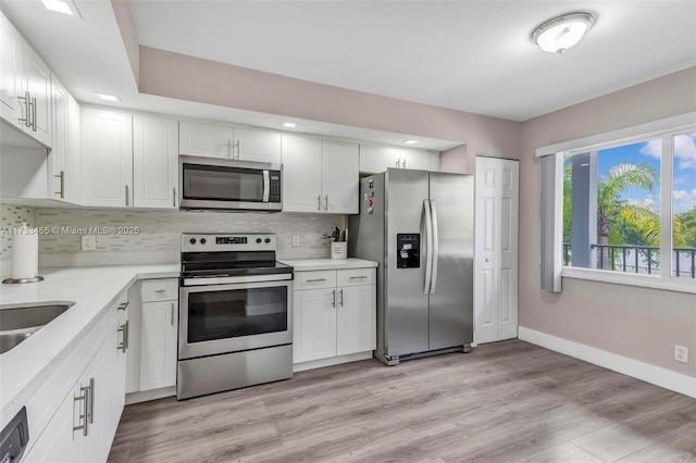 1401 SW 128th Ter Unit 307H, Pembroke Pines, FL 33027 - kitchen featuring white cabinets, appliances with stainless steel finishes, light countertops, baseboards, and decorative backsplash