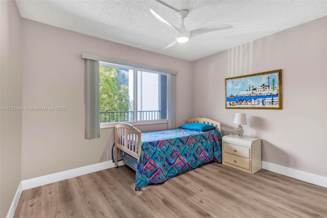 bedroom with ceiling fan, wood-type flooring, and a textured ceiling