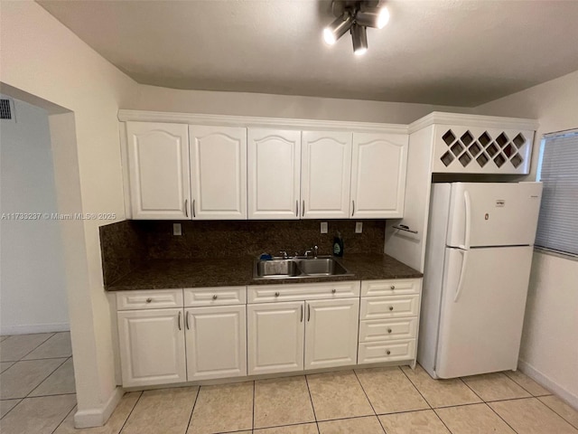 kitchen featuring sink, light tile patterned floors, backsplash, white refrigerator, and white cabinets