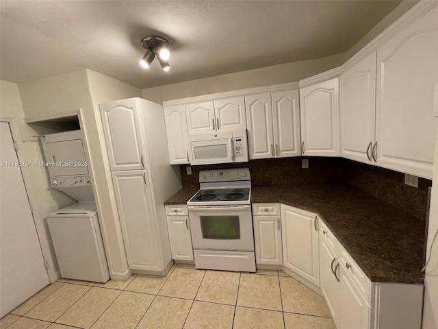 kitchen featuring white cabinetry, light tile patterned floors, white appliances, and stacked washer / dryer