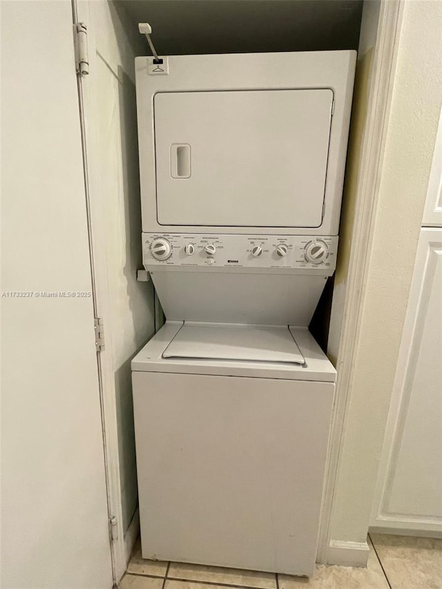 washroom featuring stacked washer / drying machine and light tile patterned floors