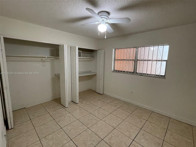 unfurnished bedroom featuring light tile patterned floors, two closets, a textured ceiling, and ceiling fan