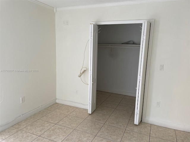 unfurnished bedroom with crown molding, light tile patterned flooring, and a closet