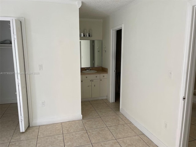 hall featuring sink, a textured ceiling, and light tile patterned floors