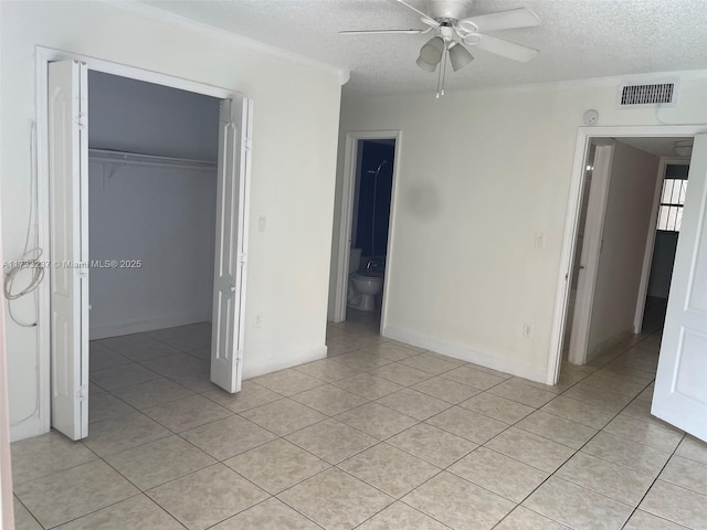 unfurnished bedroom with ensuite bath, a walk in closet, a closet, and ceiling fan