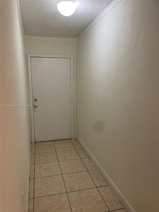 corridor featuring crown molding, light tile patterned floors, and a textured ceiling