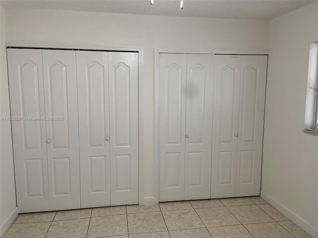 interior space featuring light tile patterned floors, a textured ceiling, and multiple closets