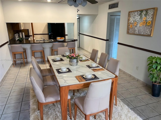 dining space featuring ceiling fan, sink, and light tile patterned floors