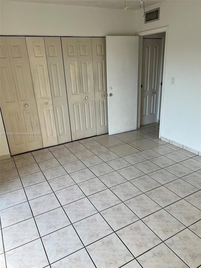 unfurnished bedroom featuring light tile patterned flooring and a closet