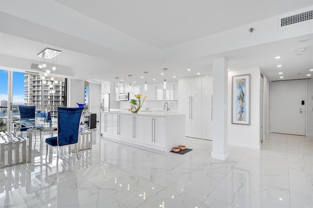 interior space with sink, an inviting chandelier, decorative light fixtures, a center island, and white cabinets