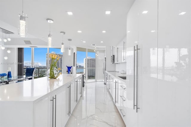 kitchen featuring a large island, decorative light fixtures, and white cabinets