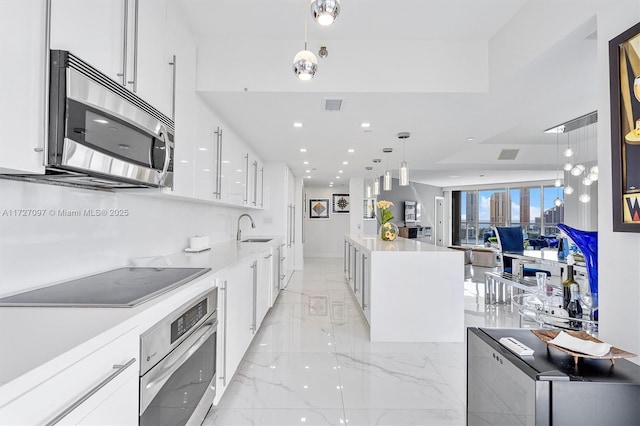 kitchen featuring pendant lighting, a kitchen island, white cabinets, and appliances with stainless steel finishes