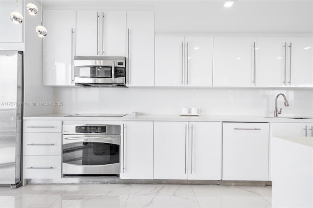 kitchen featuring stainless steel appliances, sink, hanging light fixtures, and white cabinets