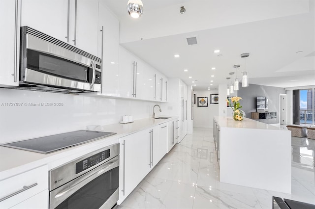 kitchen with stainless steel appliances, decorative light fixtures, sink, and white cabinets