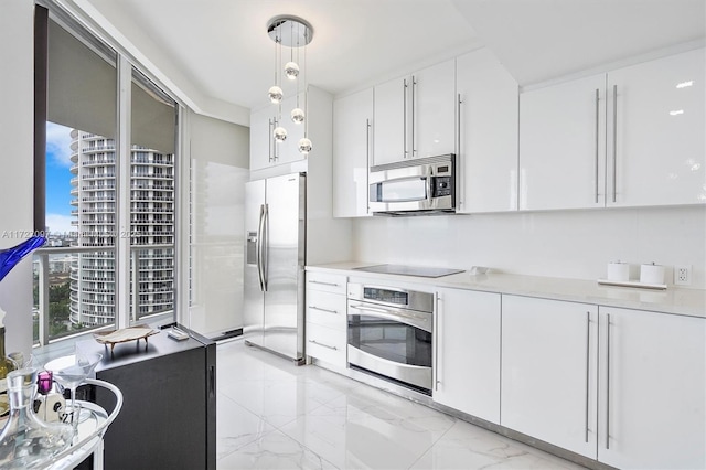 kitchen featuring pendant lighting, white cabinetry, stainless steel appliances, and a wall of windows