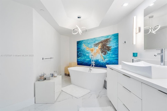 bathroom featuring a raised ceiling, vanity, and a tub